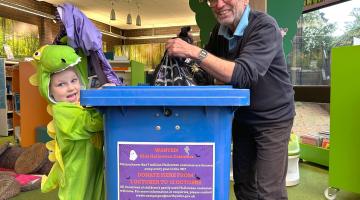 A man and child with a costume recycling bin