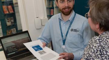 Two people with a laptop looking at a piece of paper