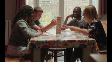 Four people at a table playing Jenga