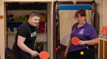 A lady and teenage boy playing table tennis 