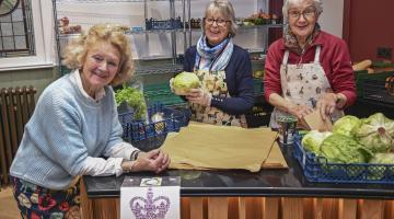 Three ladies behind a table with food