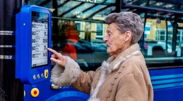 A lady looking at a bus station sign