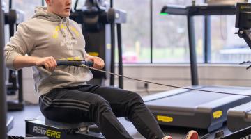 Man sat on a rowing machine in a gym