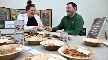Two people sat behind a table which has bowls of seeds