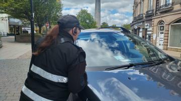 A person looking at a blue badge on a car