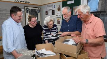 Four people looking at objects in a box