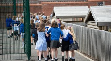 Young children walking into school with a blue uniform