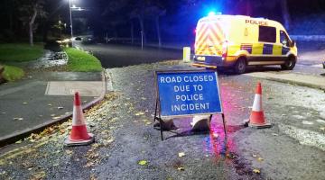 A road closure sign and police van