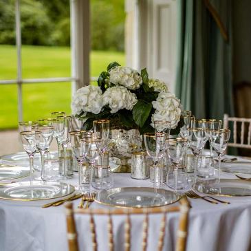 Table set with beautiful flowers and golden rimmed wine glasses. 