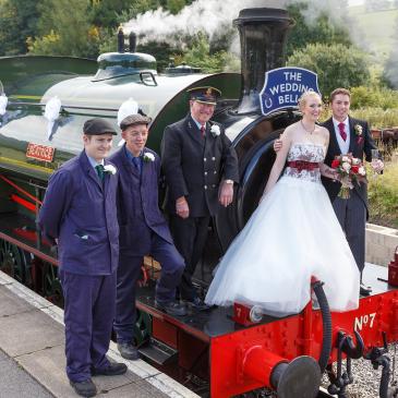 Bride and groom standing with train workers waiting on the platform.
