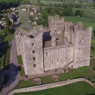 A view of Bolton Castle with sun shining and large gardens.