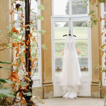 Wedding dress hanging in front of window with decorations.