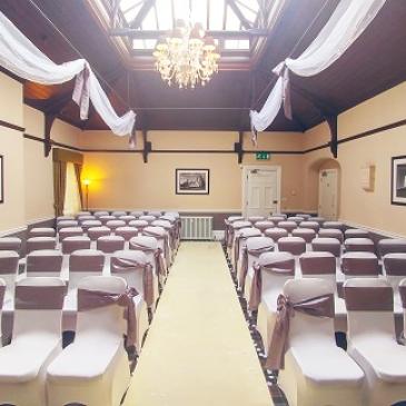 Chairs set out in rows on each side of an aisle facing a wedding ceremony.
