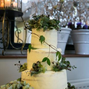 Large, beautiful wedding cake with floral decorations in the background.