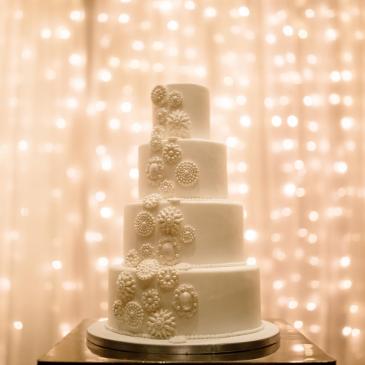 Beautiful and large wedding cake with a fairy light backdrop.