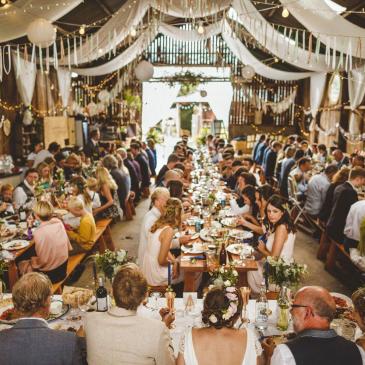 Large gathering of wedding guests in a grand barn.