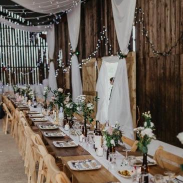 Long table with chairs and floral centre pieces.