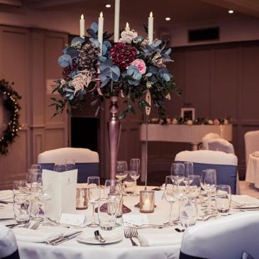 Chairs and tables set out with floral centre pieces.