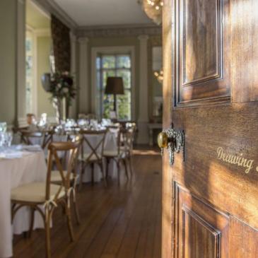 Entering the drawing room with tables and chairs set for a wedding dinner.
