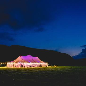 Wedding marquee glowing in a field at night.