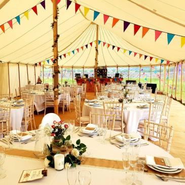 Tables and chairs laid out for a wedding meal in a marquee.