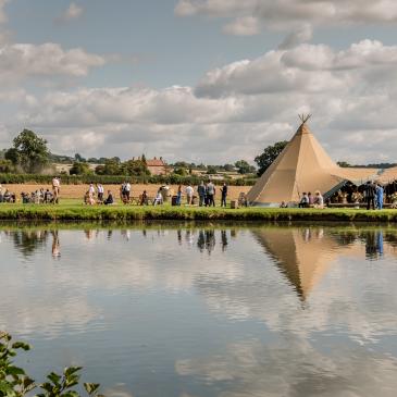 Wedding venue set up near a lake with guests having a good time.