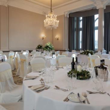 Well lit room with chandeliers and wine on tables for guests