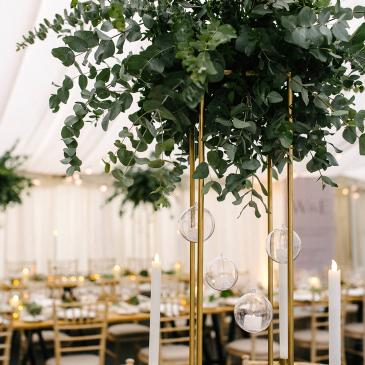 Wedding dinner tables in the background of a floral decoration. 