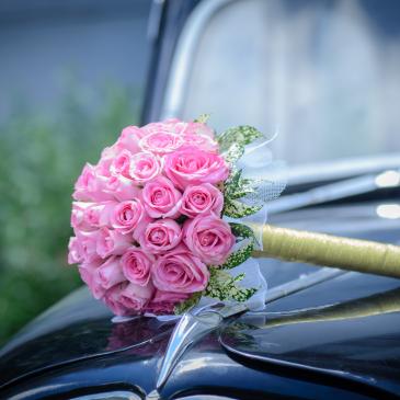 Bouquet of pink flowers on the hood of a fancy car.