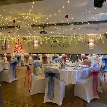 Chairs decorated with ribbons and tables set for a meal.