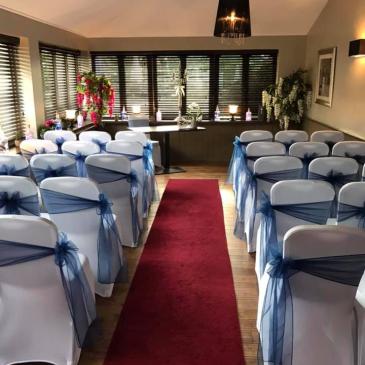Seats set out on each side of an aisle facing a wedding ceremony.