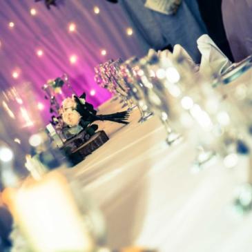 Table set out with a floral centre piece and a fairy lights backdrop.