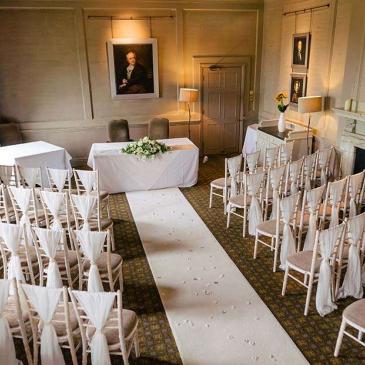 Seats set out on each side of an aisle facing towards a wedding ceremony.