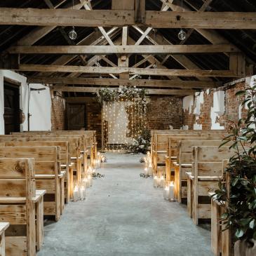 Long chairs on each side of an aisle facing a wedding ceremony.