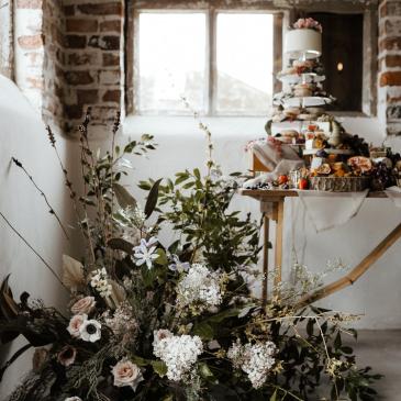 Large floral decorations sitting next to a wedding cake table.