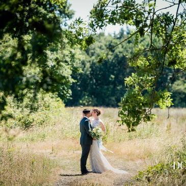 A wedding couple stood in a sunlit field
