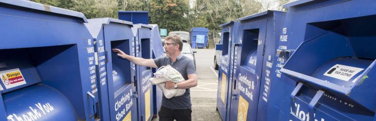 A man putting textiles in the recycling box