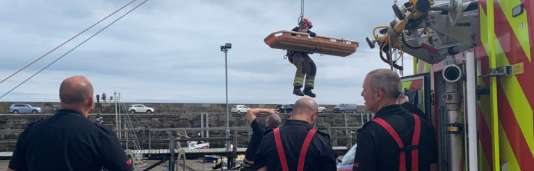 Rescue staff at an emergency incident supervising a casualty being winched to safety.