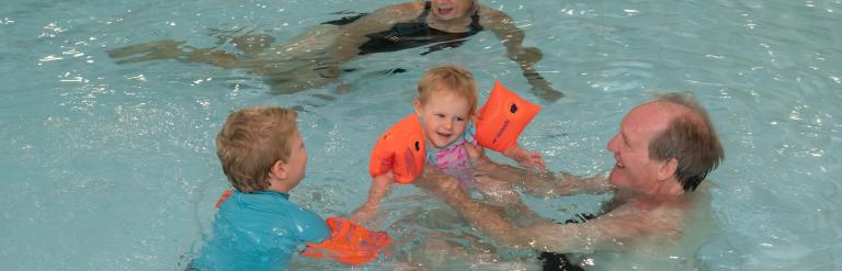 Grandparents and two young children enjoy a family swim time in the swimming pool