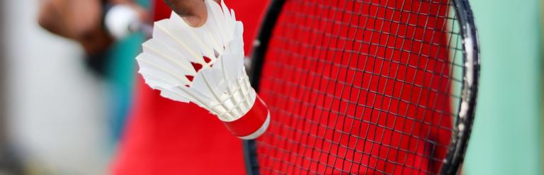 Someone holding a shuttlecock and badminton racquet, ready to serve