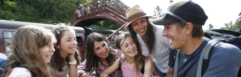 Group of people sitting talking with train and railway bridge in the background