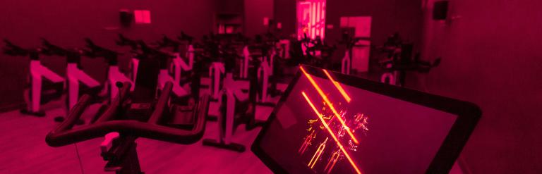 A line of spin bikes at Stokesley Leisure and Wellbeing Hub, illuminated red from the ceiling lights
