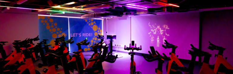 Exercise bikes set up ready for a spin class at Thirsk and Sowerby Leisure and Wellbeing Hub, a sign on the wall reads "Let's ride"