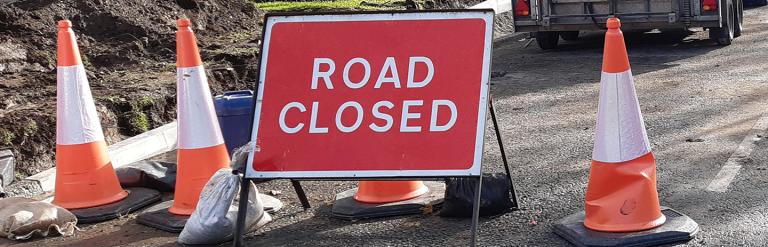 Road closed sign between highway cones