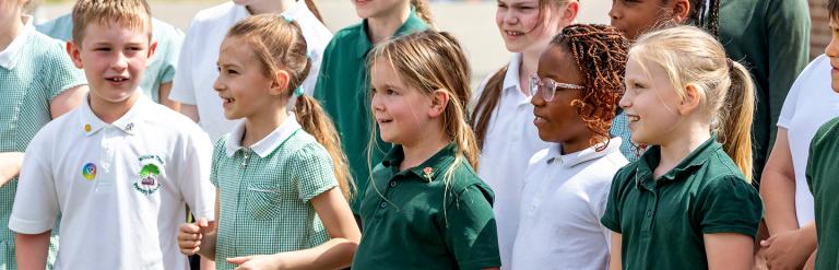 Group of primary school children standing singing outside.
