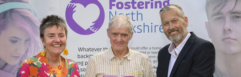 Three people smiling in front of a Fostering North Yorkshire banner