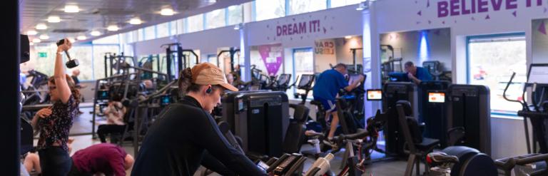 A view of Skipton Leisure and Wellbeing Hub gym, people can be seen on exercise bikes, treadmills and lifting weights.