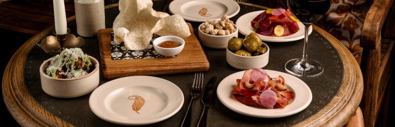 Selection of bar snacks presented on a round wooden table with a lit candle