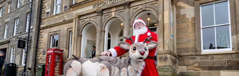 Father Christmas and a panto reindeer outside Skipton Town Hall