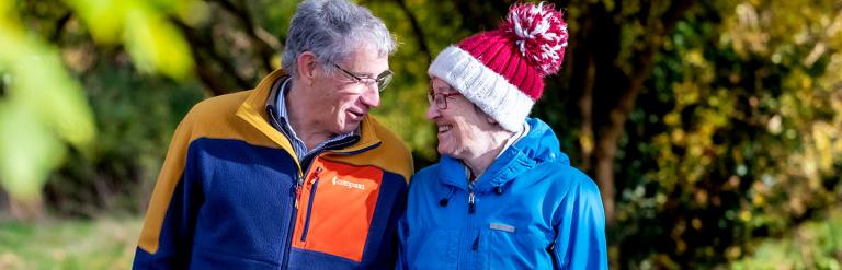 Couple walking outside on an autumn day looking at each other smiling